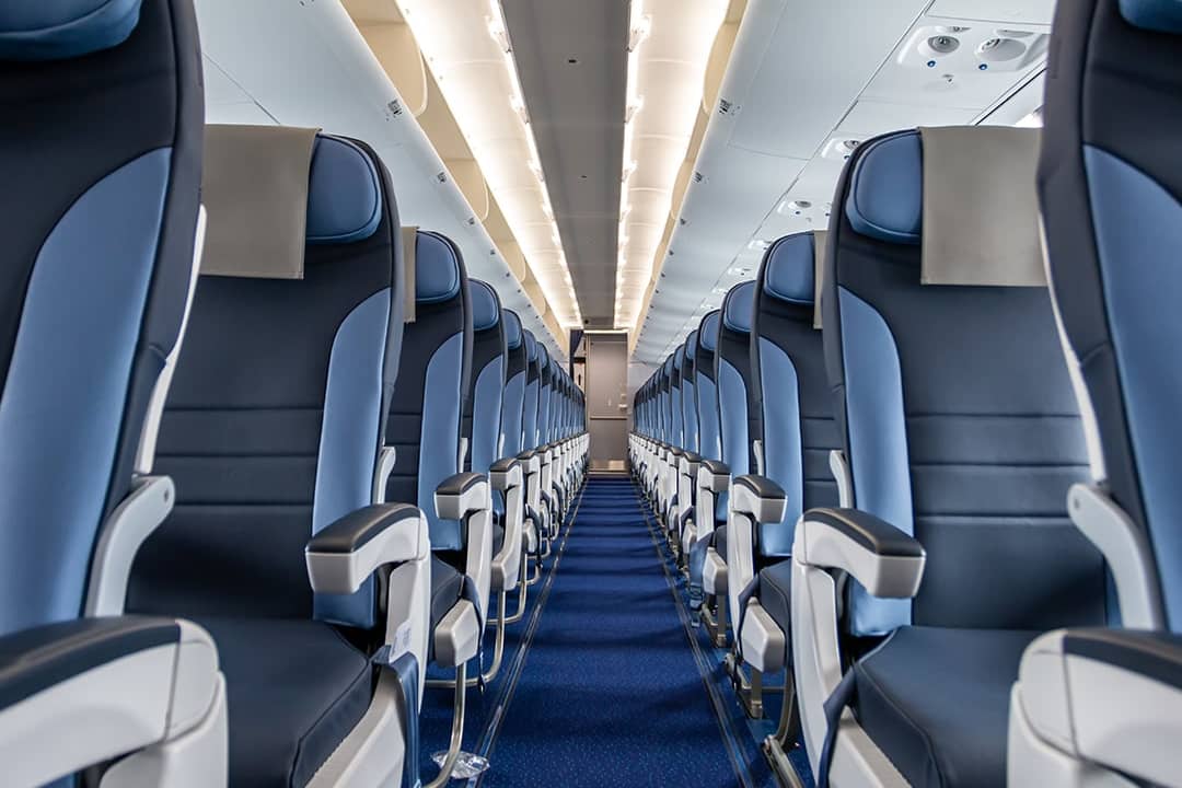 An interior cabin of an empty commercial aircraft lining a central aisle.